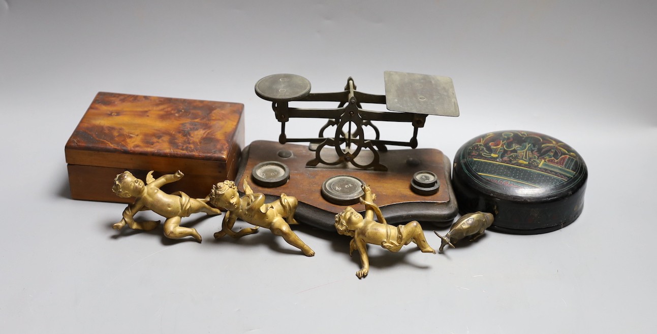 A set of three 19th century cast bronze cherubs, a set of lacquer coasters, a postal scale and a yew box